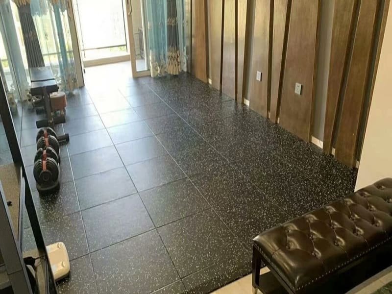 Un installatore professionista lascia una fessura di espansione per la posa di un pavimento in gomma per palestra